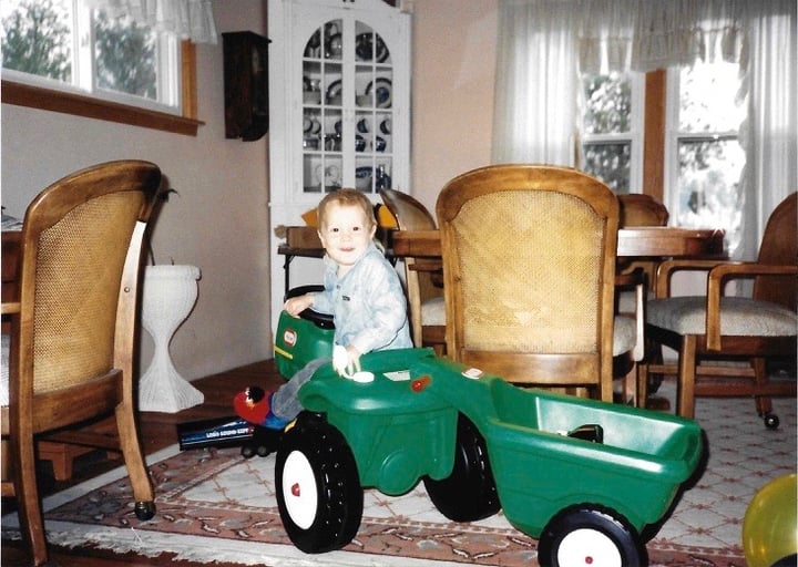 Jesse as a child playing in a toy tractor